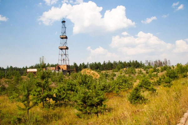 Mavi gökyüzüne ve ön plandaki tarımsal çevreye karşı kıyıda bir sondaj platformu. Gaz sahasının keşfi için endüstriyel ekipman fotoğrafı.
