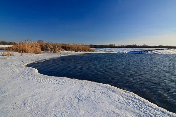Donmuş gölü ve günbatımı gökyüzü olan güzel bir kış manzarası. Doğanın bileşimi.
