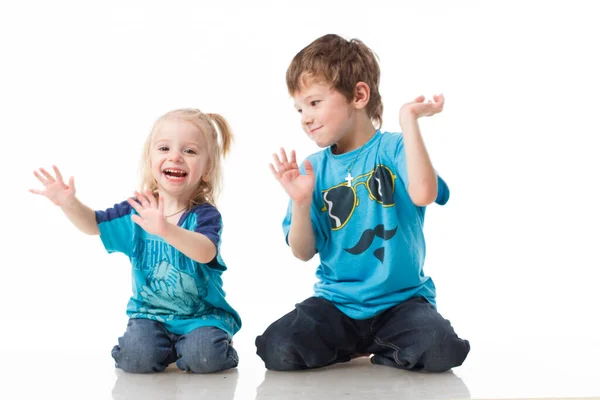 Portrait d'un frère et d'une sœur, blonds bouclés aux yeux bleus riant joyeusement sur fond blanc. Enfant émotions, bonheur, joie, plaisir. Beaux enfants mignons. Amitié. — Photo