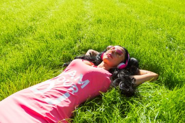 Güzel bir kız öğrencinin parkta geçirdiği ve baş parmağını gösterdiği yatay bir portre. Memlekette eğlenen neşeli genç bir bayan. Hafta sonu ve tatil konsepti. Yüksek kalite fotoğraf