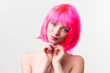 Pembe arka planda izole edilmiş şekerlerle poz veren peruklu güzel bir kadının görüntüsü