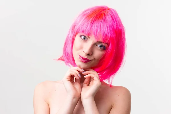 Immagine di eccitata bella donna in parrucca ridere mentre posa con caramelle isolate su sfondo rosa — Foto Stock