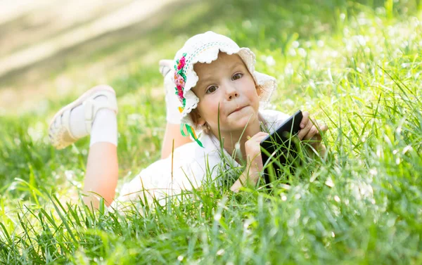 Gadis kecil yang lucu berbaring di rumput — Stok Foto