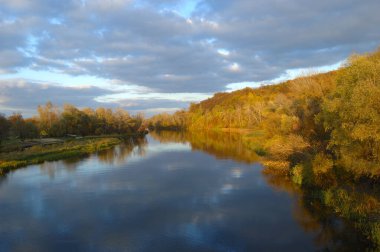 Sonbaharda göl kenarında gün doğumu, yükselen güneşin arka ışığında göl, sonbahar ve sonbaharda park sabah güneş ışığında park, suda renkli yapraklar, sonbaharda suyun yanında ağaçlar.