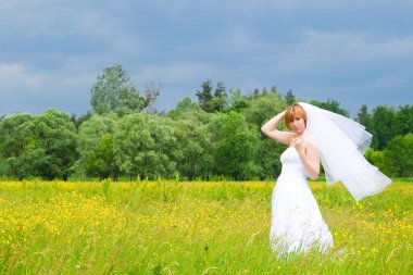 Düğün günü, güzellik, doğa konsepti. Tarlanın ortasında beyaz gelinlik giyen harika bir kadın var. Kendi etrafında dönüyor ve pullar güneşin ışığında parlıyor.