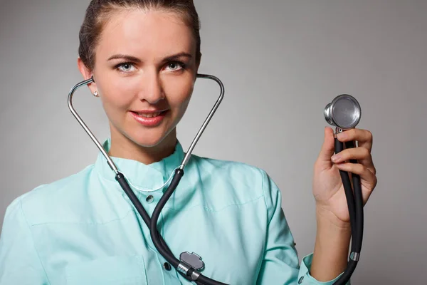 Doloroso al petto. Focalizzato medico femminile fiducioso utilizzando stetoscopio durante la diagnosi di salute e posa sullo sfondo isolato — Foto Stock