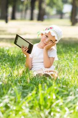 Sevimli küçük kız çimlerin üzerinde yatıyor.