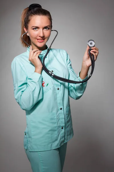 Επώδυνο στο στήθος. Εστιασμένη γυναίκα γιατρός με αυτοπεποίθηση χρησιμοποιώντας στηθοσκόπιο κατά τη διάγνωση της υγείας και θέτοντας στο απομονωμένο υπόβαθρο — Φωτογραφία Αρχείου