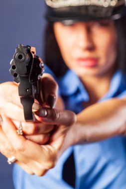 Stüdyoda silahlı üniformalı bir kız poz veriyor. Vurgu, ön planda yer alan silahta..