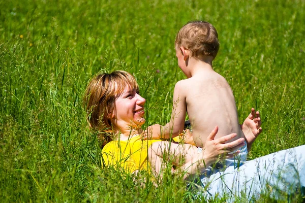 Genç anne ve bir yaşındaki kızı parkta çimlerin üzerinde dinleniyorlar. Aile birlikte eğleniyor.. 