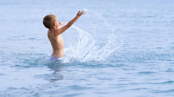 Šťastný chlapec se světlovlasými vlasy a s úsměvem v bazénu Stock Snímky