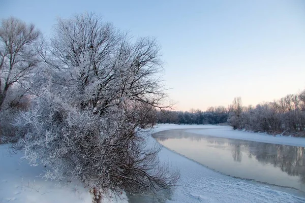 照片上覆盖着雪的河流在冬天没有结冰，河水在冬天奔流。树枝上的雪。河中的雪的倒影.大雪飘落在河岸上. — 图库照片