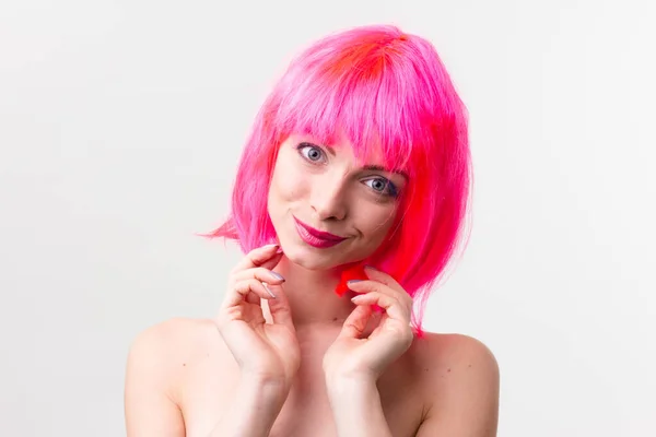 Imagem de mulher bonita animado na peruca rindo enquanto posando com doces isolados sobre fundo rosa — Fotografia de Stock