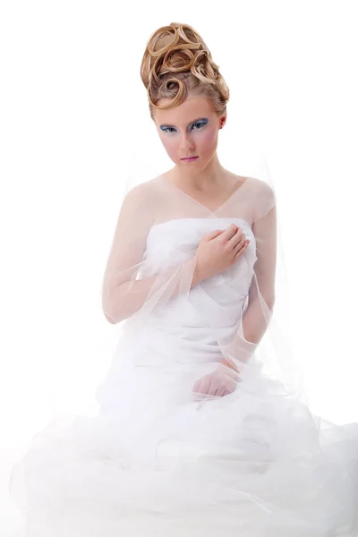 Het meisje met de lange haren in een lichte, witte jurk poseren op lichte grijze achtergrond. Studio opname, geïsoleerde afbeelding. — Stockfoto