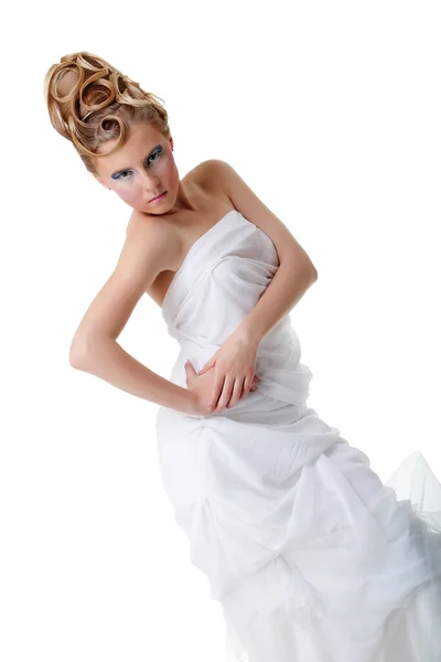Het meisje met de lange haren in een lichte, witte jurk poseren op lichte grijze achtergrond. Studio opname, geïsoleerde afbeelding. — Stockfoto