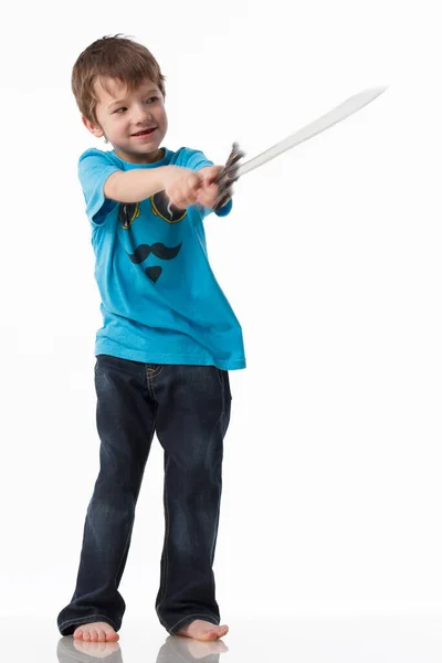Um menino posa com uma espada em um estúdio em um fundo cinza. — Fotografia de Stock