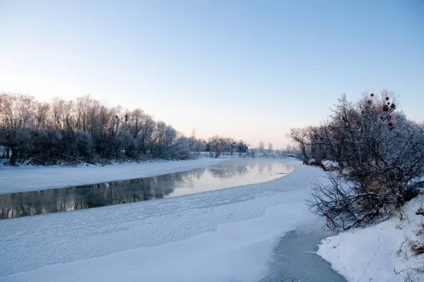 冬は雪に覆われた川が凍ることはなく、冬には川が流れる。木の枝に雪。川の雪の反射。巨大な雪のドリフトは、ストリームの銀行にある. — ストック写真
