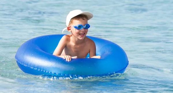 Garçon heureux avec les cheveux blonds souriant assis dans la piscine Photos De Stock Libres De Droits