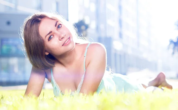 Linda chica morena con vestido elegante relajante al aire libre en hierba verde y huele a limón aromático o cítricos de lima —  Fotos de Stock