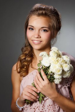 Çiçek açan bir bahçede çekici bir genç kızın güzel portresi. Hasır şapkalı ve beyaz elbiseli kıvırcık saçlı kadın. Yeni sezon konsepti