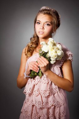 Çiçek açan bir bahçede çekici bir genç kızın güzel portresi. Hasır şapkalı ve beyaz elbiseli kıvırcık saçlı kadın. Yeni sezon konsepti