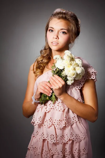 Çiçek açan bir bahçede çekici bir genç kızın güzel portresi. Hasır şapkalı ve beyaz elbiseli kıvırcık saçlı kadın. Yeni sezon konsepti