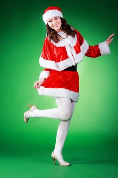 Beautiful emotional young girl with long hair, dressed as Santa Claus, posing on a green chrome background. Stok Resim