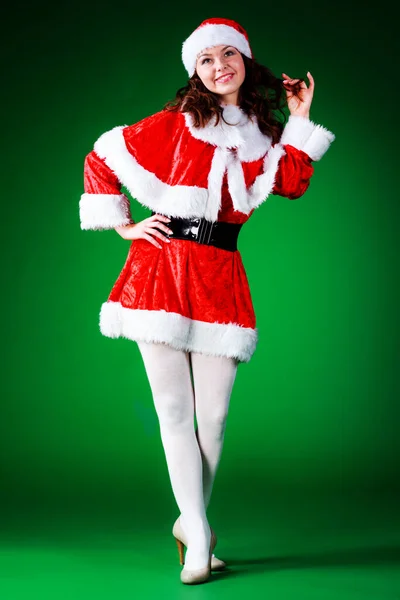 Belle jeune fille émotionnelle aux cheveux longs, habillée comme le Père Noël, posant sur un fond vert chromé. Photo De Stock