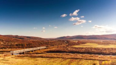 Ukrayna 'daki Stryi Nehri üzerindeki demiryolu köprüsünün havadan görüntüsü. Nehir boyunca uzanan güzel bir kırmızı demiryolu köprüsü, tepeler arasında muhteşem bir vadide yer alıyor..