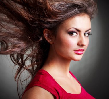 Kırmızı boğazlı kazak gülümseyen içinde çekici kıvırcık saçlı esmer kız