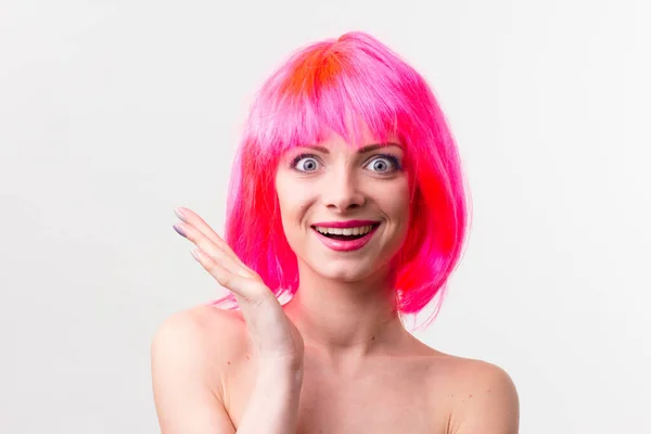 Imagem de mulher bonita animado na peruca rindo enquanto posando com doces isolados sobre fundo rosa — Fotografia de Stock