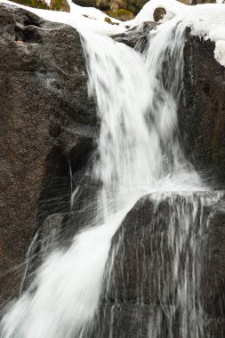 Küçük, aktif bir şelale. Temiz dağ deresi, karlı kış manzarası, vahşi yaşam geçmişi