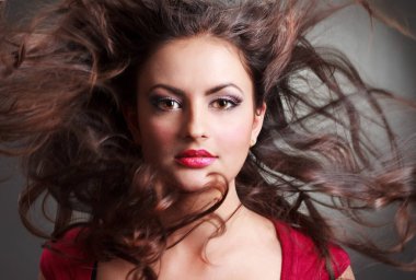 Kırmızı boğazlı kazak gülümseyen içinde çekici kıvırcık saçlı esmer kız