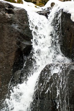Küçük, aktif bir şelale. Temiz dağ deresi, karlı kış manzarası, vahşi yaşam geçmişi