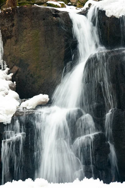Küçük, aktif bir şelale. Temiz dağ deresi, karlı kış manzarası, vahşi yaşam geçmişi