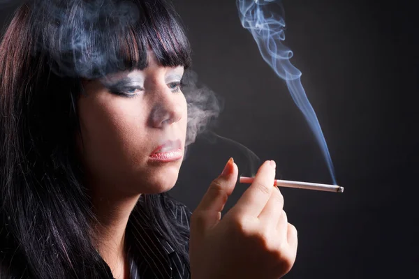 Mulher fumante com fumaça de cigarro no fundo preto — Fotografia de Stock