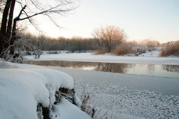 Photo the snow-covered river did not freeze in winter.The river flows in winter. Snow on the branches of trees. Reflection of snow in the river. Huge snowdrifts lie on the Bank of the stream. Stock Image