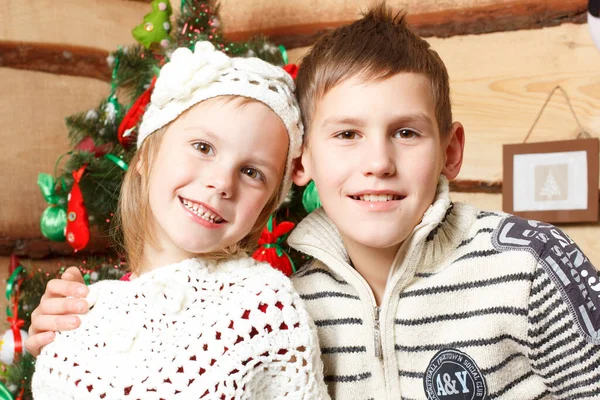 Ritratto di ragazzo felice nell'abbraccio della sorella, entrambi guardando la macchina fotografica la sera di Natale — Foto Stock