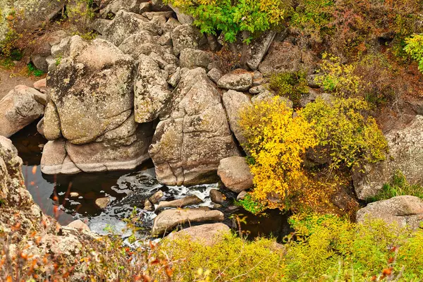 Ένας μεγάλος αριθμός των πετρωμάτων που καλύπτονται με πράσινη βλάστηση που βρίσκεται πάνω από ένα μικρό ποτάμι στη γραφική Ουκρανία και την όμορφη φύση της — Φωτογραφία Αρχείου