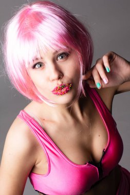 Pembe arka planda parlak makyajlı, at kuyruklu genç bir kadının yüzü..