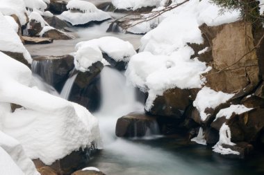Küçük, aktif bir şelale. Temiz dağ deresi, karlı kış manzarası, vahşi yaşam geçmişi