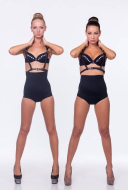 Stüdyoda kadın ikili. İki kız arka planda sarılıyor. İç çamaşırlı şehvetli mankenler.