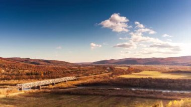 Ukrayna 'daki Stryi Nehri üzerindeki demiryolu köprüsünün havadan görüntüsü. Nehir boyunca uzanan güzel bir kırmızı demiryolu köprüsü, tepeler arasında muhteşem bir vadide yer alıyor..