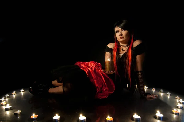 Menina bonita com cabelo vermelho, vestindo um longo vestido de renda de flamenco preto e vermelho gótico com espartilho preto. ajoelhado no chão. isolado em fundo branco. — Fotografia de Stock