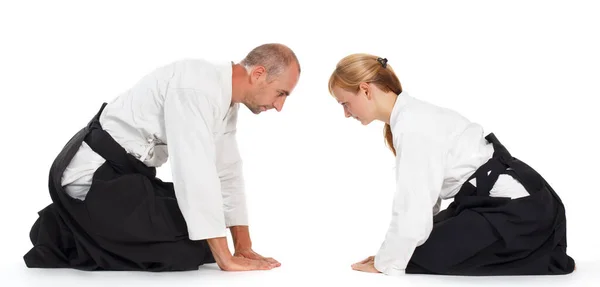 Deux personnes, un homme et une femme, pratiquent l'aikido sur le tapis. Isolé sur fond blanc. — Photo