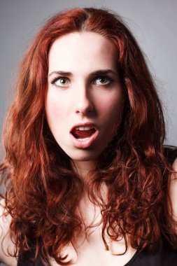 Güzel kızıl saçlı, kıvırcık saçlı tatlı kız kameraya bakıyor ve gülümsüyor. Yüzünde nazik bir makyaj olan kız. Kızın yüzünde çiller. Neşeli, neşeli, pozitif, gülümseyen kız..