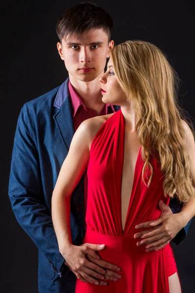 Mulher em um vestido vermelho e homem em um traje estão posando — Fotografia de Stock