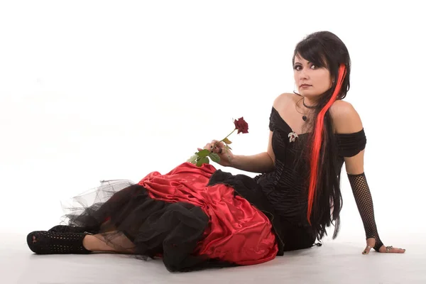 Hermosa joven de pelo rojo, vestida con un largo vestido de encaje flamenco negro gótico y rojo con corsé negro. arrodillado en el suelo. aislado sobre fondo blanco. —  Fotos de Stock