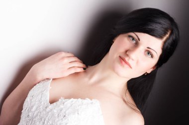 Uzun kıvırcık saçlı, iç çamaşırlı, beyaz arka planda oturan ve poz veren şehvetli bir kız. Moda tarzı portre. Güzel kızıl saçlı Umman..