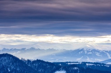 Karla kaplı dağ zirvesi rüzgarla esiyor. Kış manzarası. Güneşin altında parlayan karla soğuk bir gün..